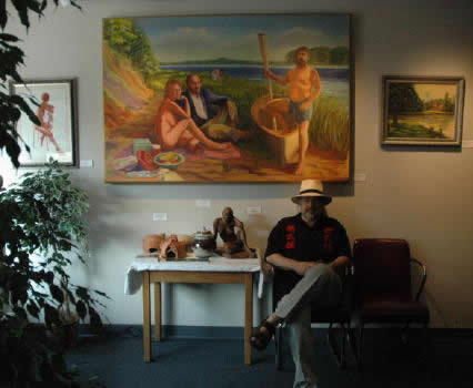 John Jensen seated in front of one of his paintings